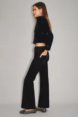 Pantalón de jean con acabado de terciopelo color azul marino, de tiro medio y corte sutilmente acampanado. Presenta cierre y botón frontal, con ruedo ancho como detalle.