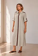 Vestido midi chemise de lino color beige, con cierre frontal de botones, cuello camisero, mangas cortas con vuelta y detalles en marrón oscuro en la botonera y los hombros.