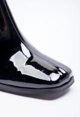 Botín negro de charol con caña media, punta cuadrada, cierre lateral y tacón bloque.