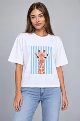 Remera de algodón blanca, de corte holgado y manga corta, con estampa frontal que muestra una jirafa sobre un fondo de rayas celestes.