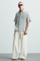 Camisa de manga corta con cuello solapa, confeccionada en tejido de mezcla de lyocell con textura de efecto arrugado y cierre frontal de botones.