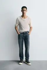 Pantalón de jean corte slim fit, color gris con efecto lavado. Presenta diseño de cinco bolsillos, cierre frontal con cremallera y botón, y tejido elástico.
