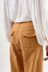 Pantalón de vestir color camel, tiro alto, corte recto y ancho, con puños doblados en el ruedo.