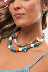 Collar corto compuesto por cuentas grandes de piedra turquesa irregular, alternadas con cuentas circulares blancas, naranjas y lilas.