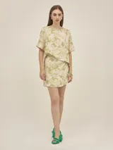 Falda corta cruzada confeccionada en mezcla de lino y viscosa, con estampado de flores y tigres en tonos verde y beige. Presenta un diseño de la marca Polonio con ajuste regulable.