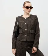 Casaqueto femenino de corte recto y largo corto, confeccionado en tejido estructurado con textura chevron. Presenta escote redondeado sin cuello, manga larga, cierre frontal con botones visibles y bolsillos decorativos con solapa.