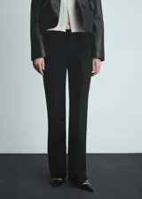 Pantalon de vestir negro de corte acampanado, con tiro bajo y cierre oculto. Presenta diseño de traje con bolsillos de ribete en la parte posterior.