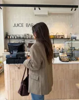 Blazer de corte relajado con diseño cuadrillé en tonos beige y marrón. Presenta hombros levemente estructurados, cierre cruzado con un botón y solapas clásicas.