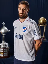 Camiseta de fútbol Umbro del Club Nacional de Football, modelo Home 2026. Diseño blanco con tejido jacquard que presenta un patrón sutil de copas históricas. Incluye cuello en V con detalles en azul y rojo, logo de Umbro, escudo del club y sponsor Antel en el frente.