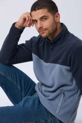 Buzo de polar térmico con diseño bicolor en tonos azul marino y celeste. Presenta cuello alto con medio cierre frontal, mangas largas y bolsillos laterales con cierre.