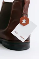 Bota tipo Chelsea de cuero negro con paneles elásticos laterales, suela de goma con detalle de vira en contraste y tirador trasero.
