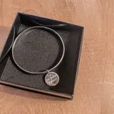 Pulsera rígida de plata 925 con dije redondo grabado.