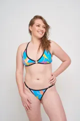 Corpiño de bikini con estampado de hojas en tonos azules y violetas, con aro metálico en el centro del busto y tirantes finos regulables que se cruzan en la espalda.