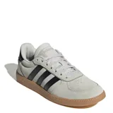 Championes Adidas modelo Breaknet Sleek, de diseño urbano y minimalista. Presentan un exterior en gamuza color gris claro con las icónicas tres tiras laterales en negro. Cuentan con una suela de goma color caramelo que aporta un estilo retro y mayor tracción.