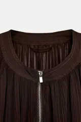 Chaqueta de organza plisada color marrón oscuro, con cuello redondo, cierre frontal con cremallera metálica, mangas largas con puños elásticos y bajo con acabado elástico.
