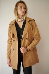 Trench coat color beige, de corte midi, con diseño de doble abotonadura, solapas clásicas y correas ajustables en los puños.