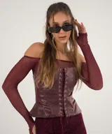 Conjunto de top y minifalda color borgoña. El top es strapless con mangas largas de tul y corpiño de cuero sintético. La minifalda es de cuero sintético con cordones laterales.