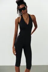Mono de poliamida color negro con escote halter y escote en V profundo, de corte ajustado y largo por encima de la rodilla.