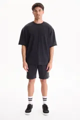 Remera oversize gris oscuro con efecto lavado, cuello redondo y mangas cortas amplias.