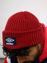 Gorro tipo beanie de punto acanalado en color azul, con parche frontal bordado que incluye el logo de Umbro y la palabra Nacional.