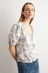 Camisa manga corta con estampado paisley en tonos azules y marrones, escote en V y cierre frontal con botones.