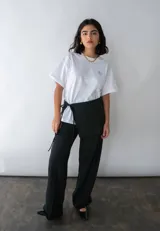 Minifalda negra para usar sobre pantalones, con lazos laterales para atar.