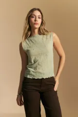 Top sin mangas de jacquard color negro, con cuello cerrado y silueta recta. Presenta una textura trabajada con relieve y una terminación suavemente ondulada en el ruedo.