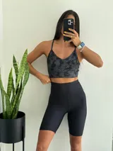 Top deportivo de tirantes finos, color negro con estampado batik en tonos grises y azul petróleo. Presenta un tejido acanalado y escote en V.