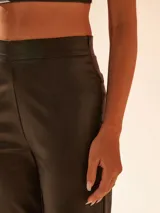 Pantalón negro de cuero sintético, corte recto y tiro alto.