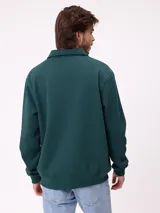 Buzo tipo polo de manga larga color bordó, con cuello camisero y cierre frontal de botones. Presenta estampado gráfico frontal con el número 85, el logo de la marca Rusty y un escudo deportivo.