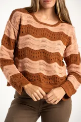 Sweater de tejido de punto con diseño de rayas horizontales onduladas en tonos marrón y beige. Presenta cuello redondo, mangas largas y corte oversize.