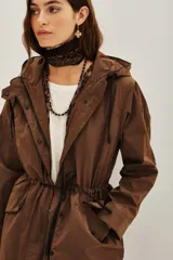 Trench color marrón con capucha, cierre frontal, cordón ajustable en la cintura y bolsillos laterales. Incluye un chaleco interior con estampado animal print.