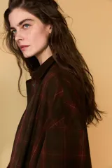 Chaqueta de mujer de la colección Zara Woman, confeccionada en algodón 100% con acabado encerado. Presenta un estampado a cuadros en tonos marrón y rojo, cuello solapa de pana, manga larga con puño y botón, bolsillos de plastrón con solapa en el delantero y cierre frontal con botones a presión.
