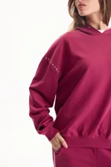 Buzo canguro deportivo de color bordó, sin friza, con capucha y detalles de tachas en las mangas.