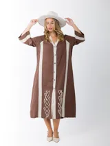 Vestido camisero marrón con rayas verticales color crema, de corte recto y largo midi. Presenta cuello en V, cierre frontal con botones y bordados en el ruedo.