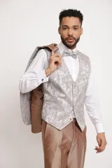 Traje de tres piezas color bronce con acabado satinado, compuesto por saco entallado, pantalón de vestir y chaleco con solapas estampadas en tonos grisáceos. Incluye moño a juego.