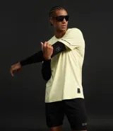 Remera deportiva de hombre con tecnología dry fit, cuello redondo y manga corta. Presenta un diseño liso en color amarillo claro con una etiqueta pequeña aplicada en el dobladillo inferior.