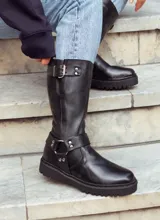 Bota de caña alta confeccionada en cuero vacuno encerado, con diseño de estilo biker. Presenta detalles de hebillas metálicas niqueladas en la caña y cierre lateral. Cuenta con suela de cuero artesanal y forrería vacuna en su interior.