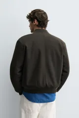 Cazadora bomber regular fit negra con cierre frontal de cremallera metálica, bolsillos de vivo en la cadera y acabados en rib elástico. El interior cuenta con efecto pelo.