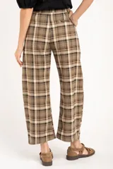 Pantalón de corte recto y tiro medio con estampado de cuadros escoceses en tonos marrones y beige. Presenta cierre frontal con botón y bolsillos laterales.