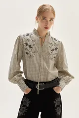 Jean de corte pata ancha color negro, con diseño de paneles frontales y bordados florales a lo largo de las piernas.