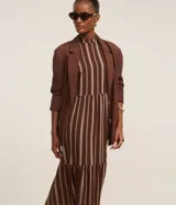 Vestido midi evasé sin mangas, confeccionado en viscosa, con cuello alto, corte en la cintura, recortes fruncidos en la pollera y rayas verticales desencontradas.