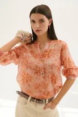 Camisa color coral con estampado floral, cuello mao y mangas 3/4 con volados.