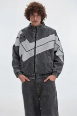 Campera de jean modelo Olimpico, con diseño en bloques de color gris oscuro y gris claro, cuello alto, cierre frontal y bolsillos laterales.