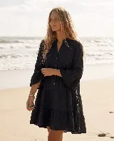 Vestido corto de lino natural color gris, con diseño amplio de capas, escote en V con botones frontales y mangas largas con volados en los puños.