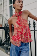 Top rojo con estampado estilo paisley, diseño de cuello halter con lazo, espalda descubierta y detalles de volantes en capas en el frente.
