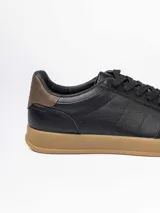 Championes urbanos de diseño minimalista en color blanco, con detalle de talón en color marrón oscuro y suela de goma color caramelo.