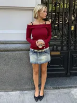 Sweater de punto trenzado color bordó, con escote estilo bote que deja los hombros al descubierto y mangas largas ligeramente acampanadas.