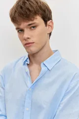 Camisa celeste de manga larga con cuello camisero abotonado y cierre frontal con botones.