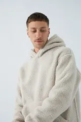 Canguro de sherpa polar color beige, con capucha, bolsillo tipo canguro y logo de goma en el pecho.